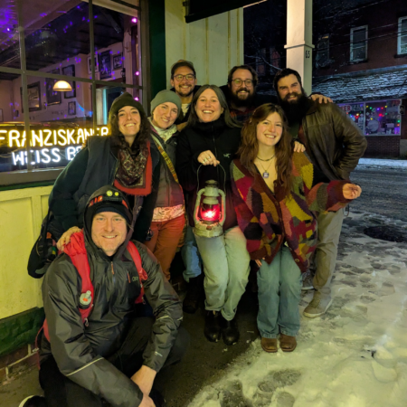 A group posing for a photo outside of a restaurant at night in the winter